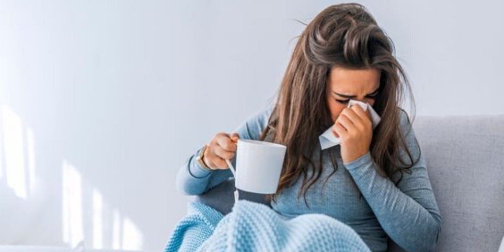 Person sitting with napkin over their mouth and nose, while holding a cup